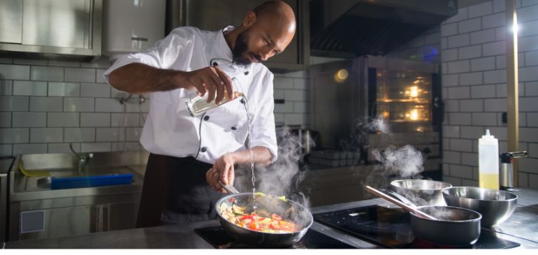 Chef preparing a flavorful dish using bold ingredients